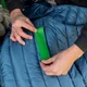 Pose d'une bande verte de la même gamme sur une doudoune, maintenue entre les doigts